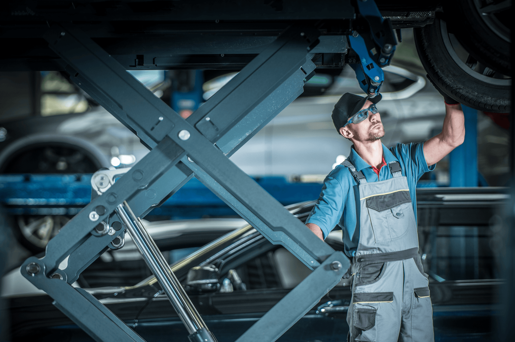 Mechanic inspecting car tire on elevated scissor lift
