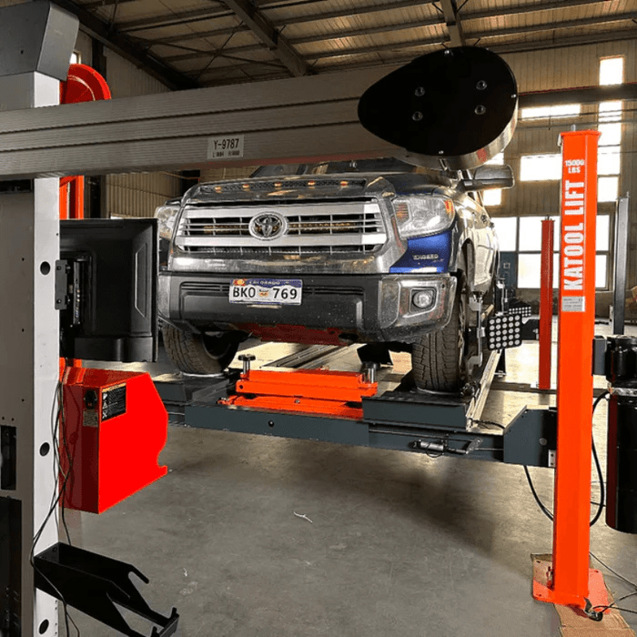 Angled view of the Katool KT-AV533 Wheel Alignment Machine aligning a pickup truck on a raised platform, with reflective targets attached for precise wheel measurements.