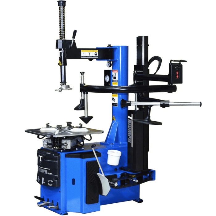 Angled view of the Triumph NTC-950-1 Tire Changer, featuring a pneumatic assist arm, foot pedal controls, and a robust turntable for efficient tire servicing.