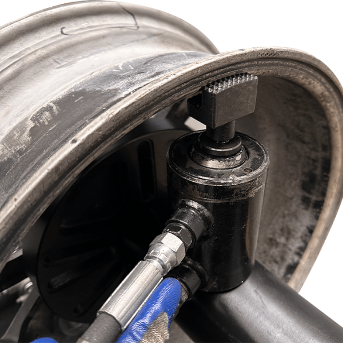 Close-up of a bent wheel rim being pressed by the Katool WL69 Rim Straightener’s hydraulic cylinder for precise repair.