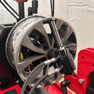 Close-up of a damaged rim mounted on the Katool KT-WL70 Rim Straightening Machine, featuring a hydraulic cylinder and clamps for precise wheel repair.