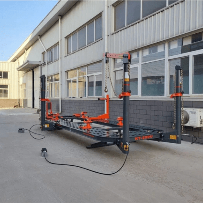 Side view of Katool KT-299U Auto Body Frame Machine setup outside industrial building, showing full-length frame and pulling towers