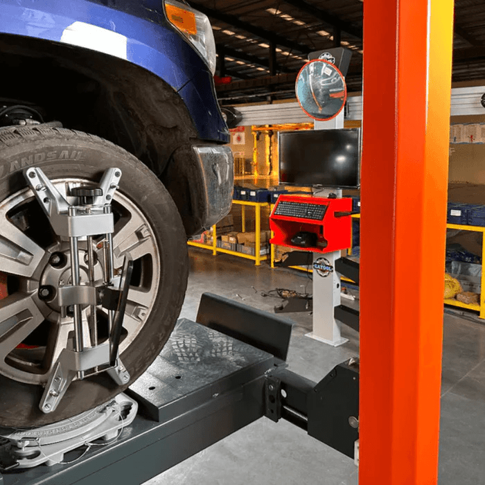 Side view of the Katool KT-AV533 High-Capacity Wheel Alignment Machine aligning a truck wheel, with a clamp assembly and digital monitor station visible.