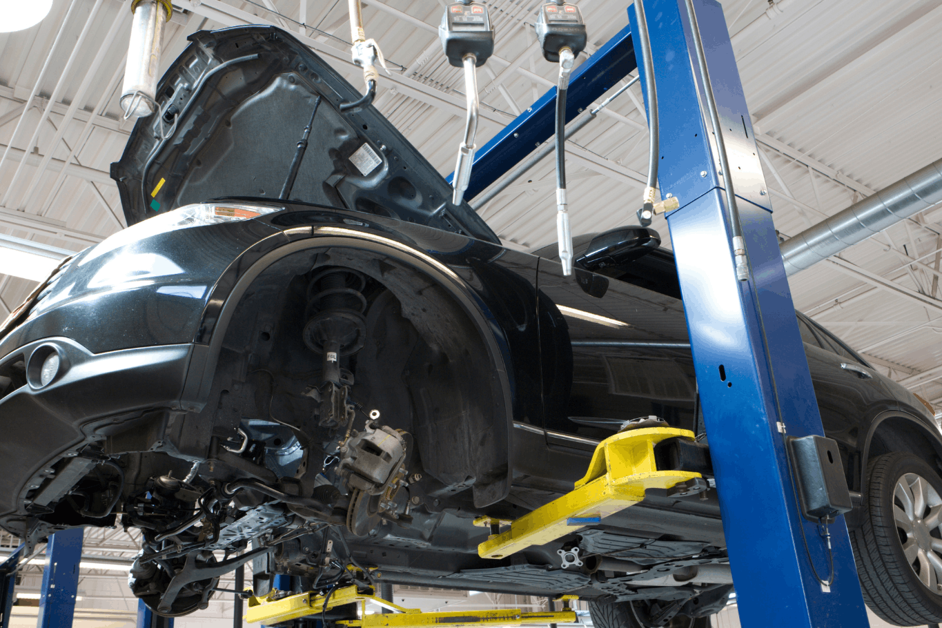 Vehicle on blue two post auto lift with wheels removed for shop maintenance