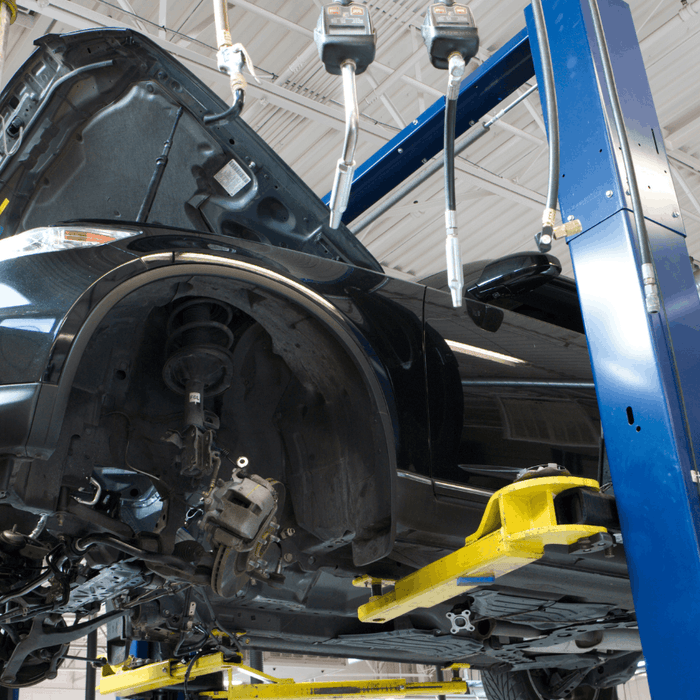 Vehicle on blue two post auto lift with wheels removed for shop maintenance