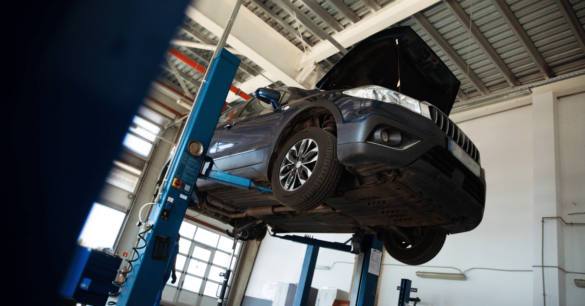 Vehicle raised on a two-post automotive lift for inspection and service in a professional garage.