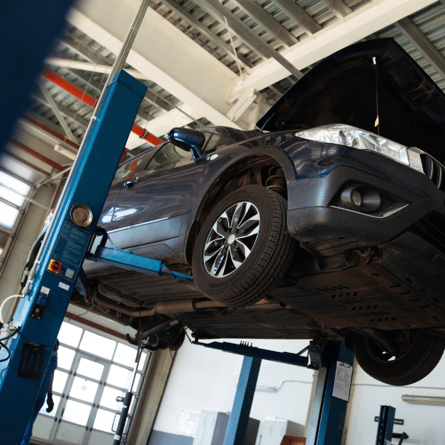 Vehicle raised on a two-post automotive lift for inspection and service in a professional garage.