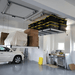 2  AuxxLifts in a garage one loaded with boxes one loaded with totes lowered right side view