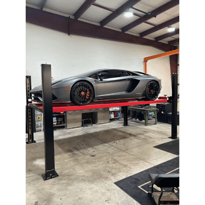 4H950 four post lift showing side view of gray sports car on red platforms in workshop setting