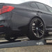 Low rear view of a BMW M3 rear wheel on a Race Ramps tow ramp at the flatbed edge
