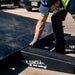 Tow operator setting a Race Ramps tow ramp against the deck of a rollback carrier