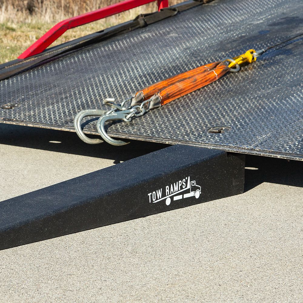 Race Ramps tow ramp positioned under the lip of a rollback bed next to the winch chain