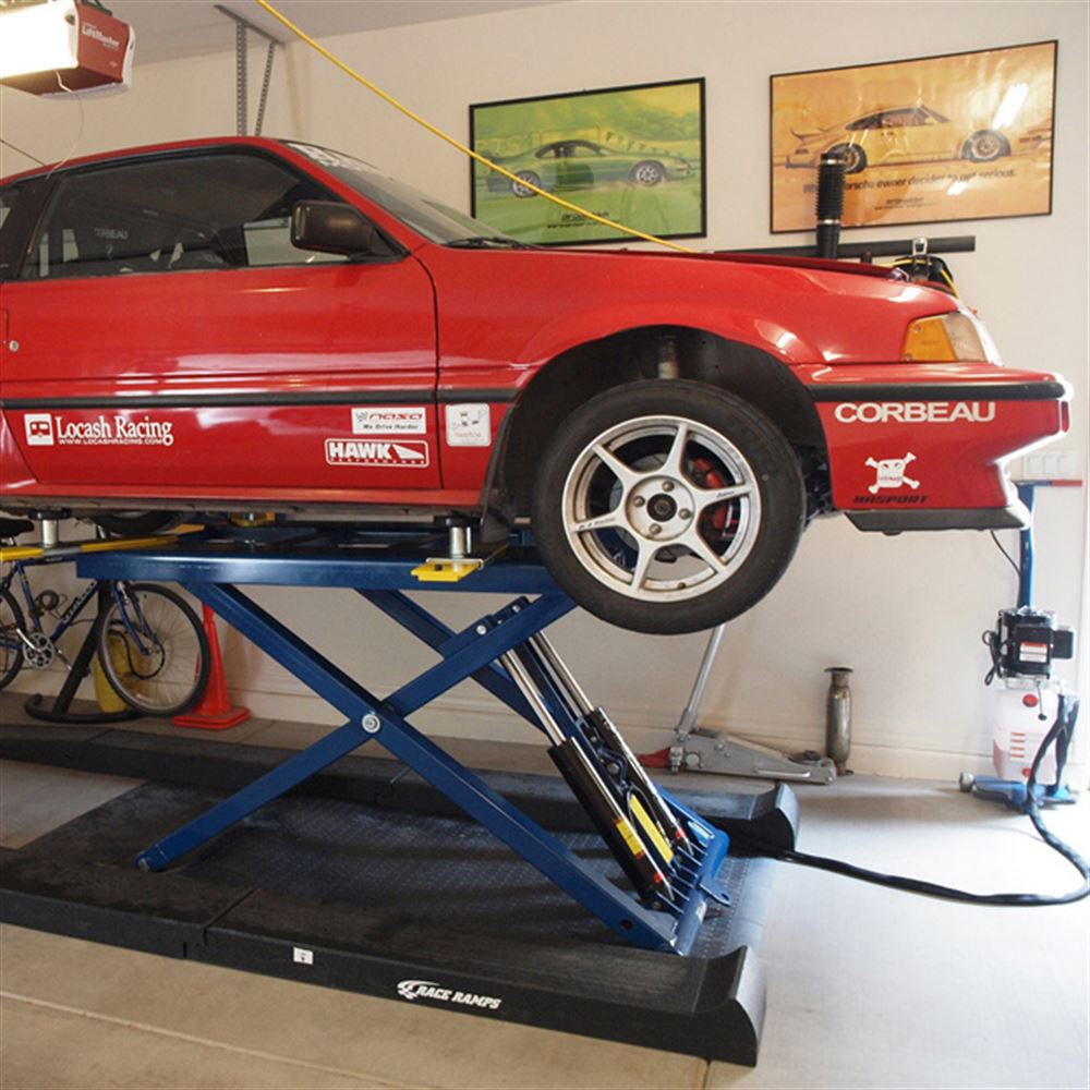 Low car raised on a scissor lift after driving up Race Ramps car lift ramps