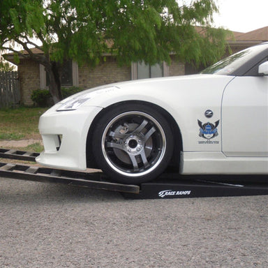 White Nissan 350Z with low front bumper rolling onto a Race Ramps RR-TR-5 trailer ramp